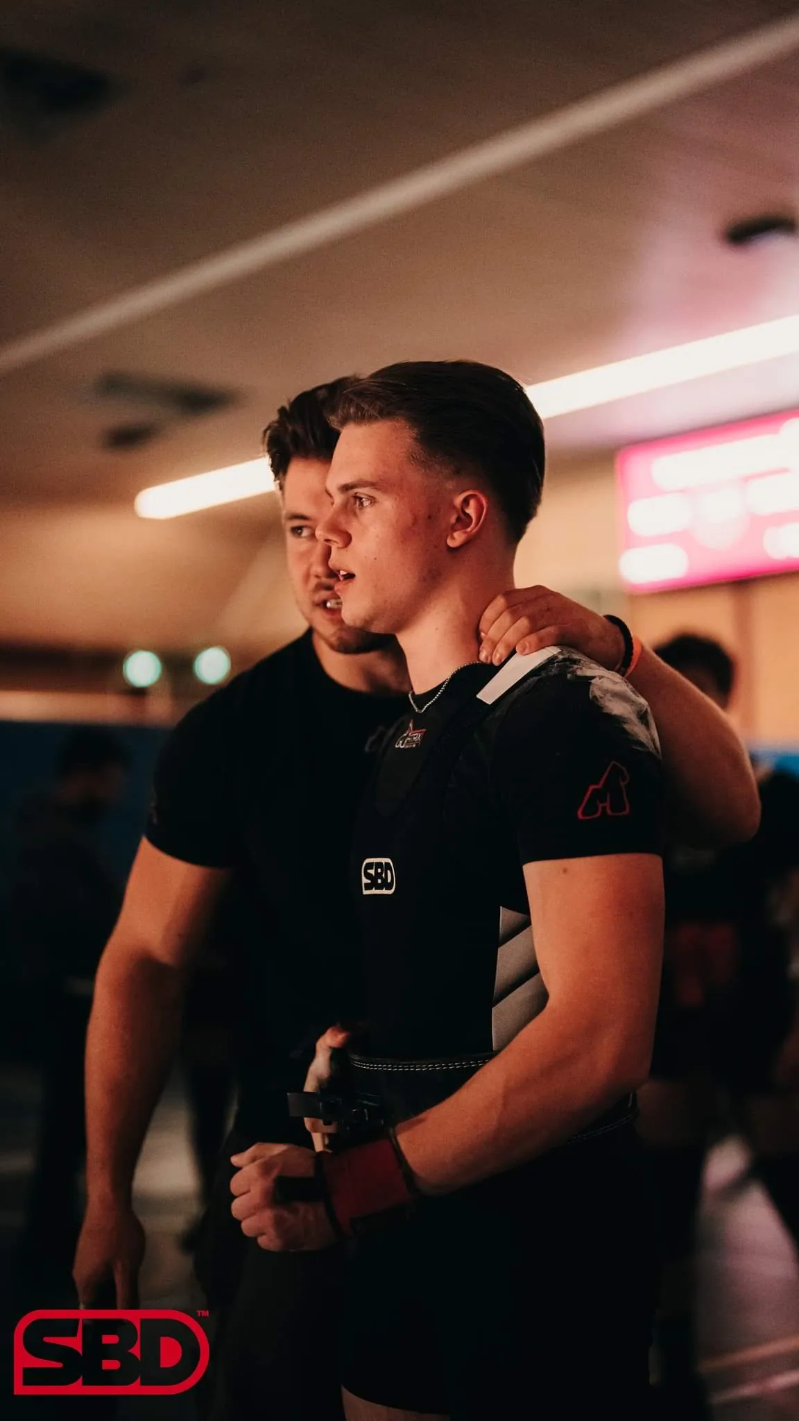 Rian spreekt een atleet moed in vlak voor diens poging op een powerliftingwedstrijd