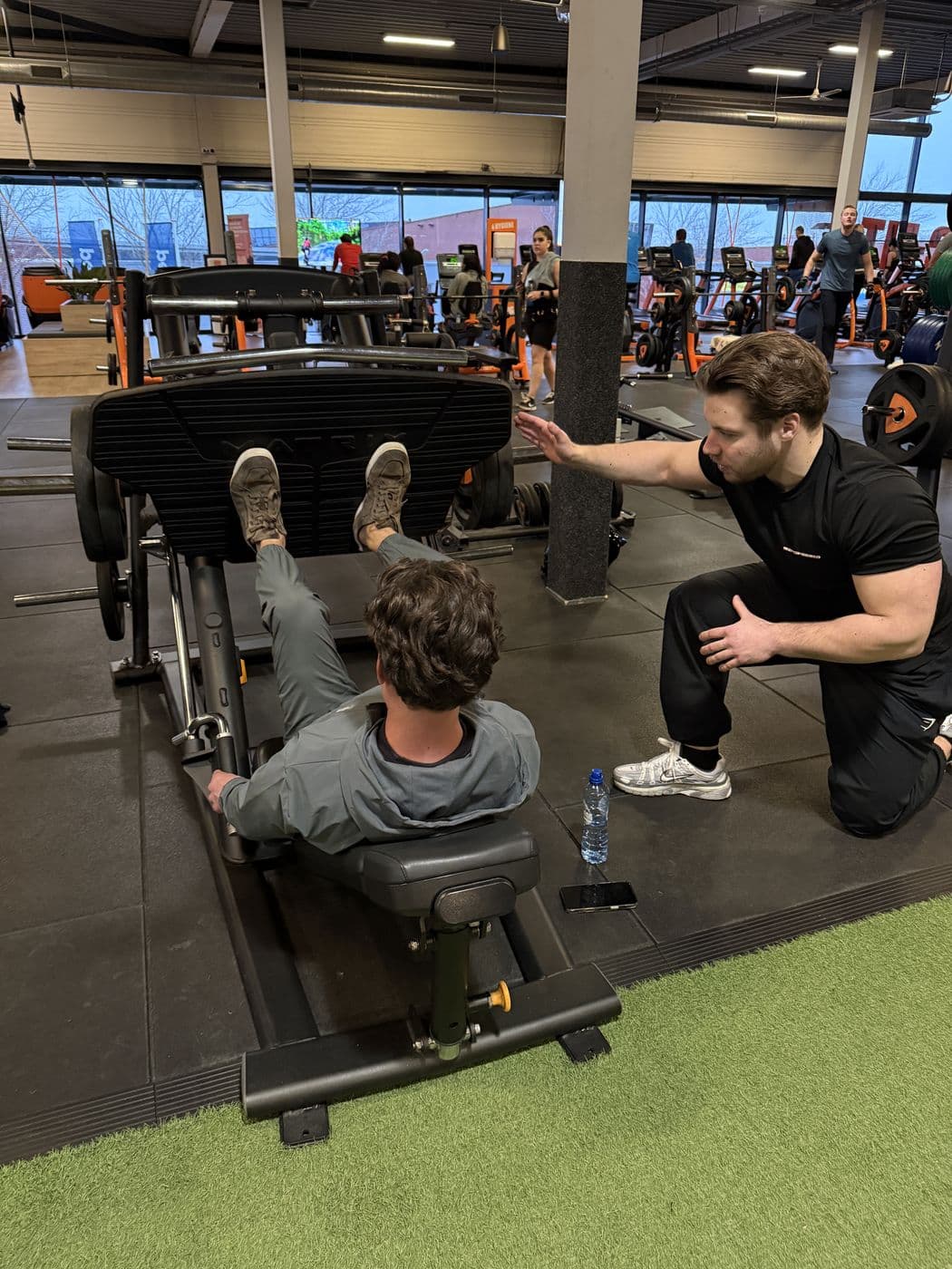 Rian coacht een klant op de legpress bij Basic-Fit Heerhugowaard