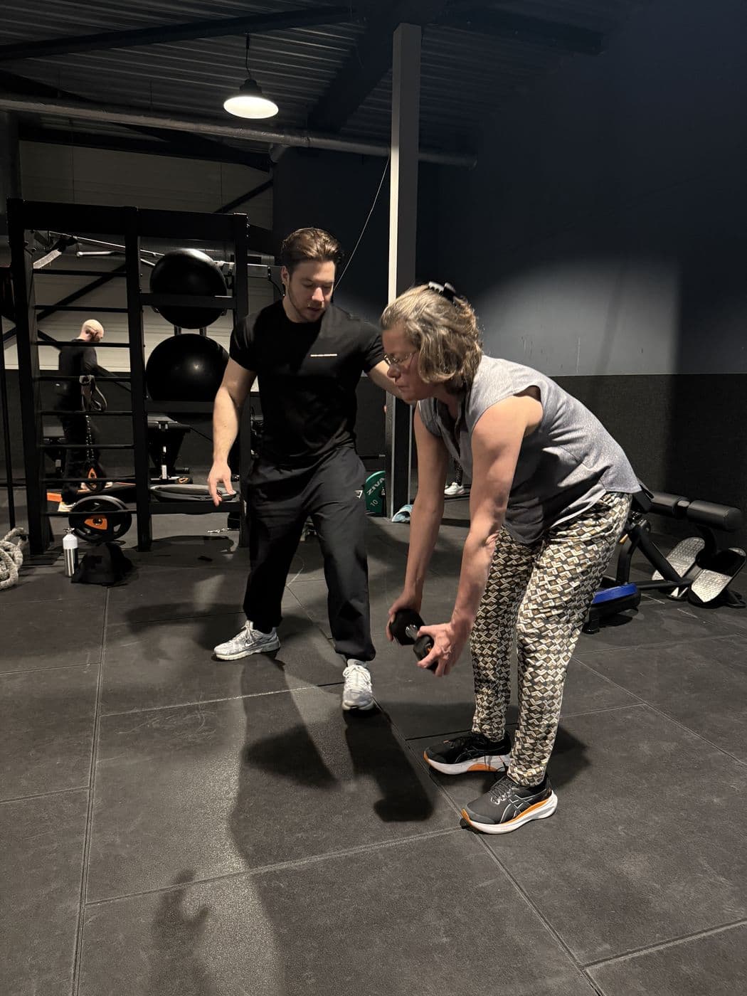 Rian legt de uitvoering van een oefening met dumbbell uit aan een klant