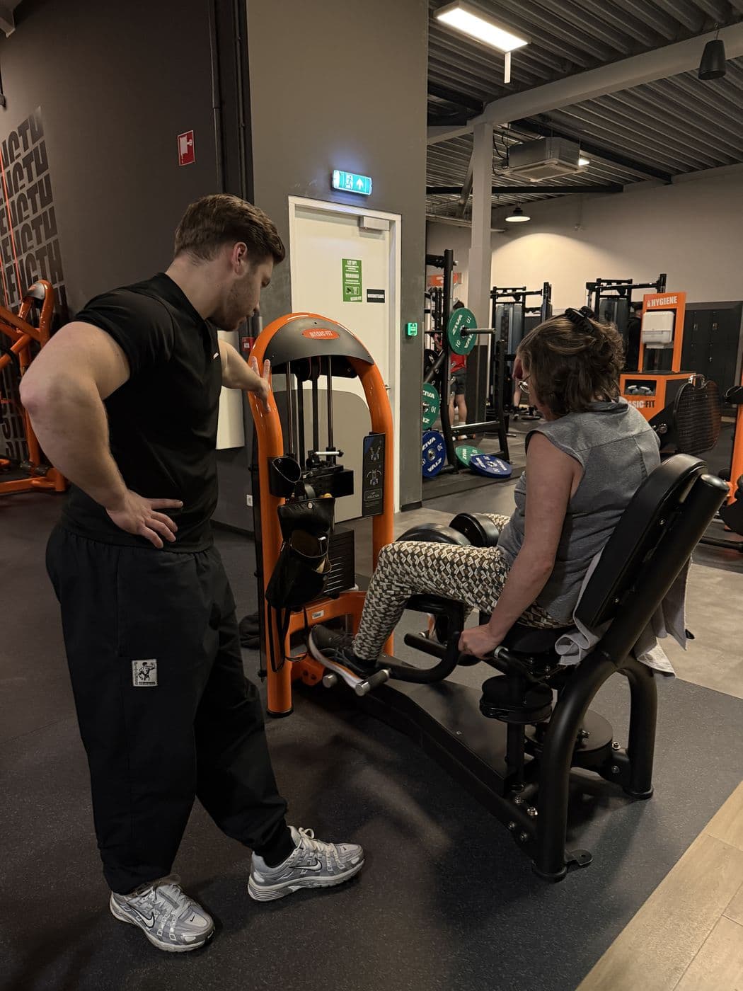 Rian begeleidt een klant op een apparaat bij Basic-Fit Heerhugowaard