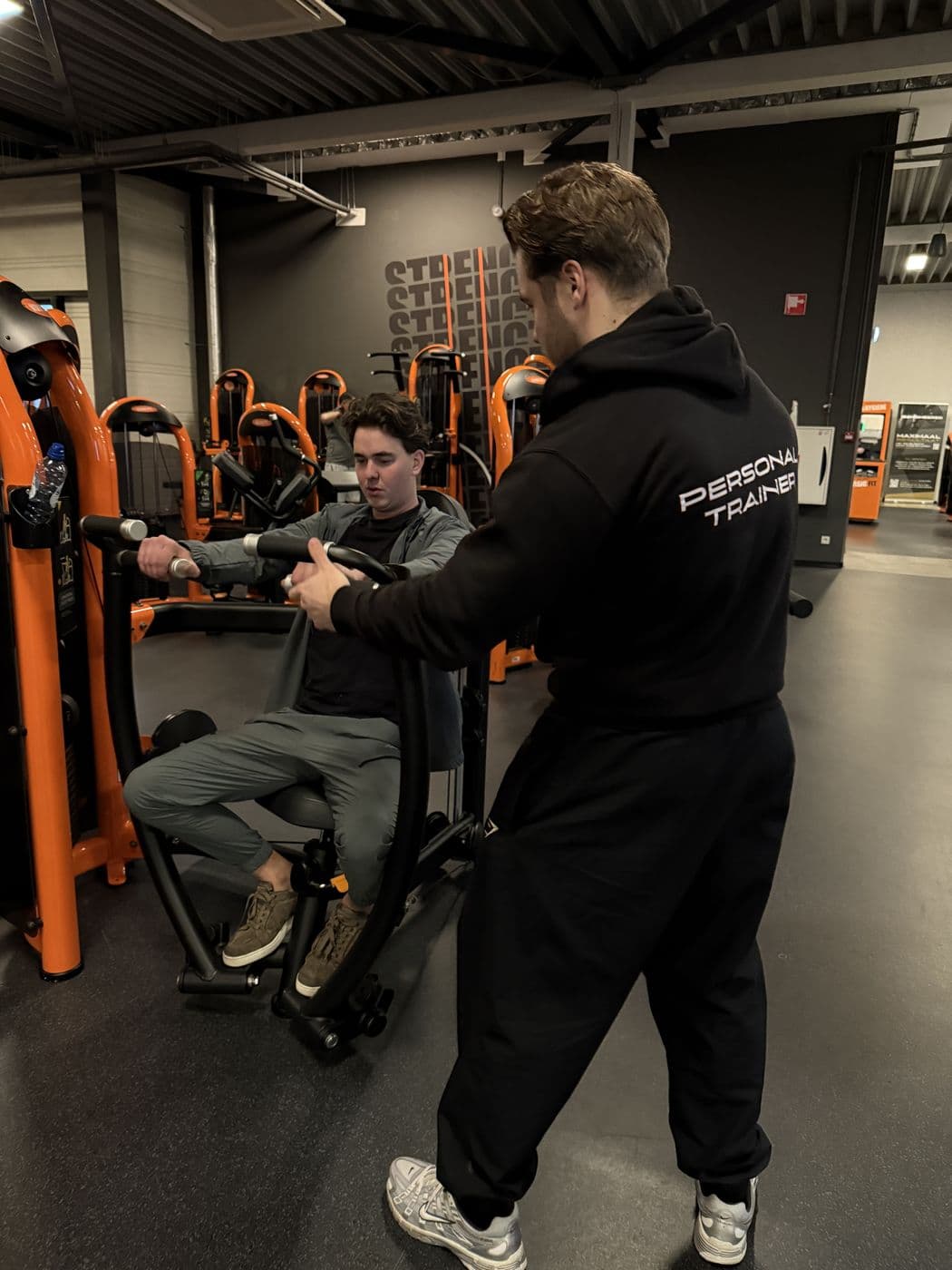 Rian coacht een klant op een apparaat bij Basic-Fit Heerhugowaard