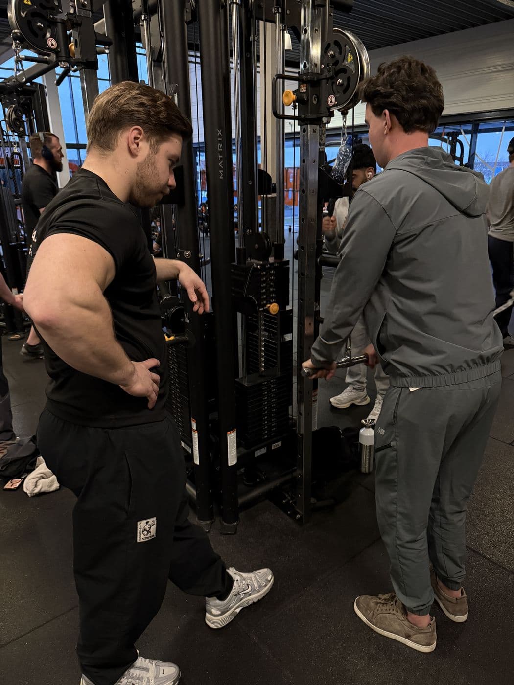 Rian legt een oefening aan de kabelmachine uit aan een klant